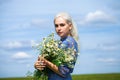 Portrait of a young blonde girl with a bouquet of chamomile in a field