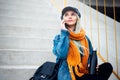 Portrait of young blonde girl, looking up, sitting on the urban stairs, talking on smartphone, holding reusable, steel thermo wate Royalty Free Stock Photo