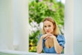 Portrait of a young blonde woman in a blue dress in a blooming lilac park near a white gazebo. Spring blooming on a sunny day