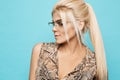 Portrait of young blonde woman with blue eyes in glasses, isolated at light blue background Royalty Free Stock Photo