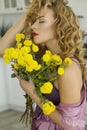 Portrait of young blonde woman at bright living room holding yellow flowers Royalty Free Stock Photo
