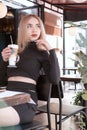 Portrait of young blonde woman in cafe. Girl enjoys latte coffee in the cafeteria. Vertical frame