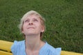 Portrait of a young blonde woman with a happy smiling face looking up. Female in a blue dress sitting on the bench Royalty Free Stock Photo