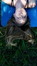 Portrait young blonde woman laying in the grass with long hair and blue eyes feeling blue and remembering up side down