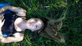 Portrait young blonde woman laying in the grass with long hair and blue eyes looking up with peaceful expression Royalty Free Stock Photo