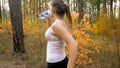 Portrait of young blonde woman running in forest and drinking water from bottle. Royalty Free Stock Photo