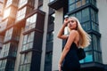 Portrait of young blonde woman wearing stylish clothing and accessories by modern business center in city. Royalty Free Stock Photo
