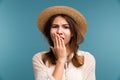 Portrait of a young bored girl in summer hat isolated over blue background,