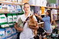 Portrait of young boy with dog during selecting dry food in petshop, woman on background