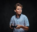 Portrait of a young boy dressed in a white t-shirt wears a wireless headset holds a control remote. on the dark Royalty Free Stock Photo