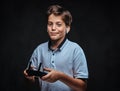 Portrait of a young boy dressed in a white t-shirt wears a wireless headset holds a control remote. on the dark Royalty Free Stock Photo