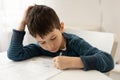 Portrait of young boy struggling with his homework at home. Children home education concept. Distance learning Royalty Free Stock Photo