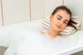 Portrait of a young brunette with eyes closed which lies in a hot tub with foam Royalty Free Stock Photo