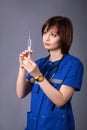 Portrait of a young brunette girl on a gray background. The medical worker holds a syringe with a vaccine in hands Royalty Free Stock Photo