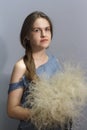 Portrait of young brunette girl in fluffy wreath of feather grass, florist girl on gray background