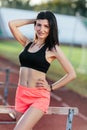 Portrait of young brunette woman athlete on stadium sporty lifestyle standing on track posing near the barriers running jumping to Royalty Free Stock Photo