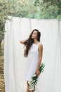 Portrait of young woman on background of white hanging textile cloth in garden Royalty Free Stock Photo