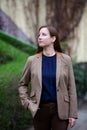 Portrait young brunette woman in brown jacket standing in front of building Royalty Free Stock Photo