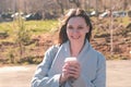 Portrait of young brunette woman in coat walks in city park and drinks coffee. Springtime. Royalty Free Stock Photo