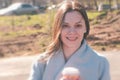 Portrait of young brunette woman in coat walks in city park and drinks coffee. Springtime. Royalty Free Stock Photo