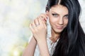 Portrait of young brunette woman fixing earring