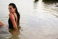 Portrait of Young Brunette Woman sits in Water at Sea. Girl in Black Swimsuit Enjoys Summer Royalty Free Stock Photo