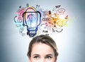 Young woman looking upwards at a colorful light bulb on a wall Royalty Free Stock Photo