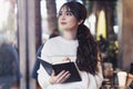 Portrait of young brunette woman standing in cafe, writing in notebook, looking out window. Girl makes notes in diary, plans Royalty Free Stock Photo