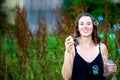 Young brunette woman standing outdoors and blowing soap bubbles Royalty Free Stock Photo