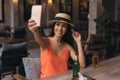 Portrait of young brunette woman taking a selfie photo from cell phone in pub bar. Royalty Free Stock Photo