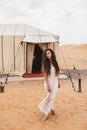 Portrait of young brunette woman in white dress. Glamping tent moroccan desert Royalty Free Stock Photo