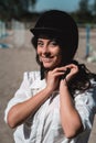 Portrait of young brunette woman in a white shirt with a helmet in a hands