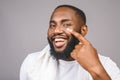 Portrait of young brutal african american man applying facial cream on his cheek. Close up portrait, men`s beauty. skin care