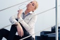 Portrait of young business fashion woman holding glasses & sitting on stairs