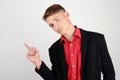 Portrait of a young business man wearing a suit and a red shirt pointing to the side. Royalty Free Stock Photo