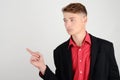 Portrait of a young business man wearing a suit and a red shirt pointing to the side, looking over. Royalty Free Stock Photo