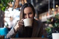 Portrait of a young business woman drinking tea from a Cup closeup with blurred restaurant background Royalty Free Stock Photo