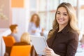 Portrait of young business woman at modern startup office interior, team in meeting in background