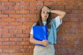 Portrait of young business woman outside office building in the alley with brick wall background standing and thinking of solving