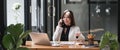 Portrait of young business woman sitting in front of her laptop and talking on mobile phone. Royalty Free Stock Photo