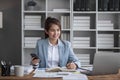 Portrait of young business woman with sitting in office in front of her laptop and talking on mobile phone hand at Royalty Free Stock Photo