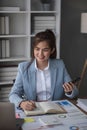 Portrait of young business woman with sitting in office in front of her laptop and talking on mobile phone hand at Royalty Free Stock Photo