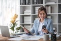 Portrait of young business woman with sitting in office in front of her laptop and talking on mobile phone hand at Royalty Free Stock Photo