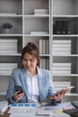Portrait of young business woman with sitting in office in front of her laptop and talking on mobile phone hand at Royalty Free Stock Photo