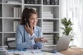 Portrait of young business woman with sitting in office in front of her laptop and talking on mobile phone hand at Royalty Free Stock Photo