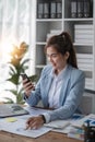 Portrait of young business woman with sitting in office in front of her laptop and talking on mobile phone hand at Royalty Free Stock Photo