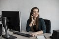 Portrait of young business woman talking phone against computer screen in white office. Female entrepreneur having call Royalty Free Stock Photo