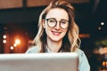 Portrait of young business woman in trendy glasses sitting in cafe,working on laptop.Blogger communicates with followers Royalty Free Stock Photo