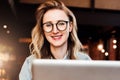 Portrait of young business woman in trendy glasses sitting in cafe,working on laptop.Blogger communicates with followers Royalty Free Stock Photo