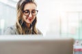 Portrait of young business woman in trendy glasses sitting in cafe,working on laptop.Blogger communicates with followers Royalty Free Stock Photo